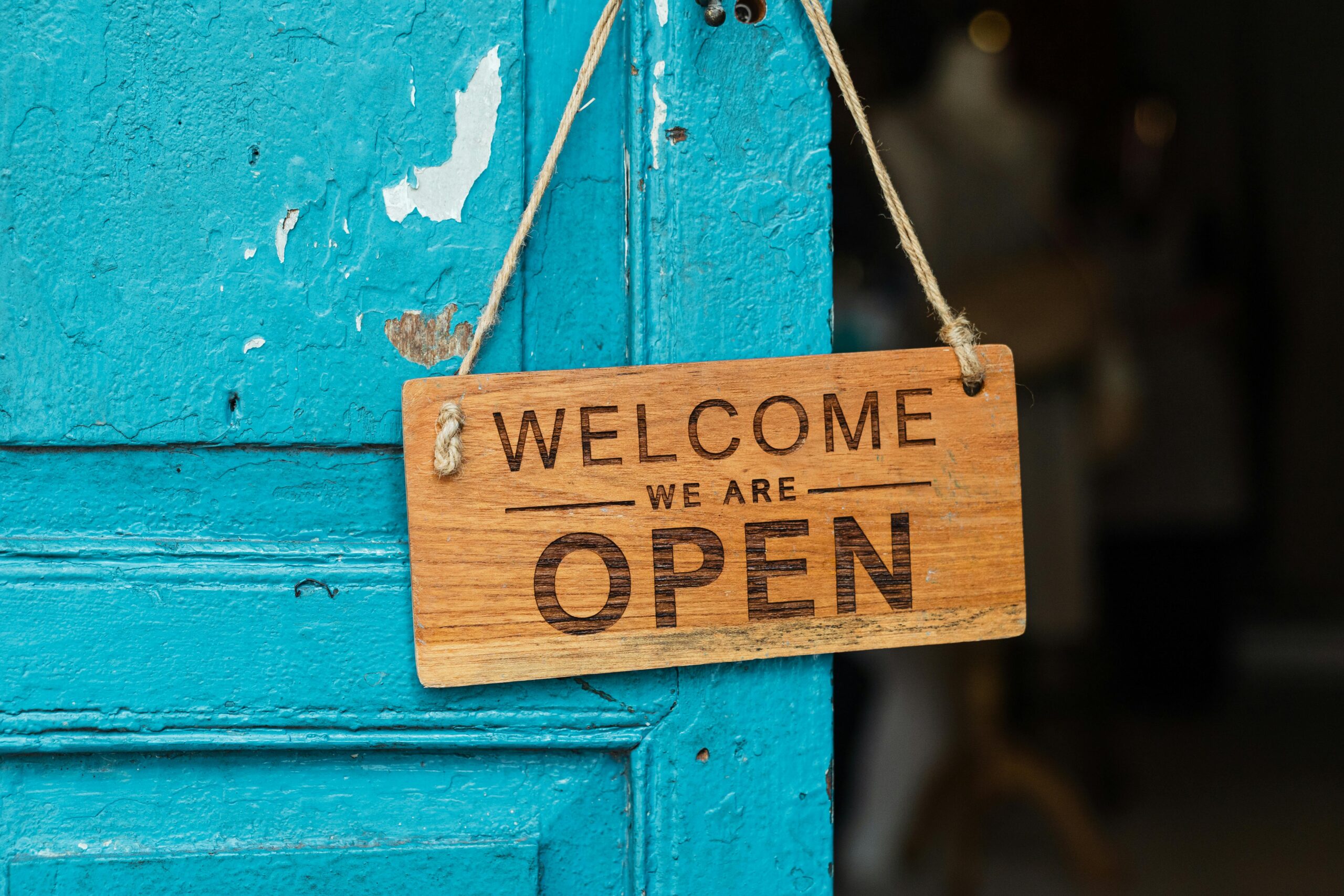 A welcome and open sign hanging on a door.
