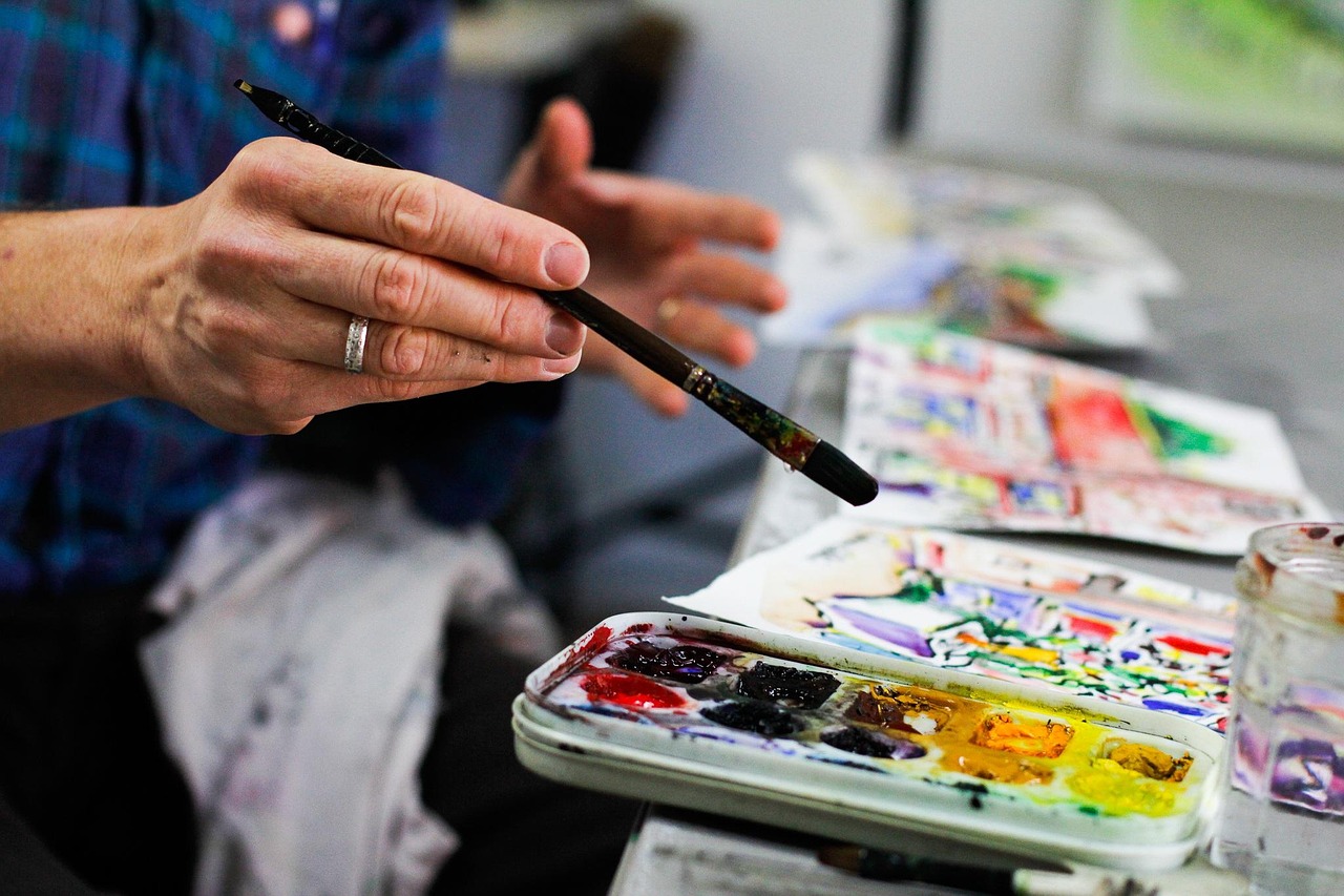 An artist's hand holding a paintbrush