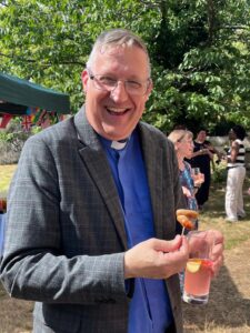 Happy vicar enjoying summer refreshments.